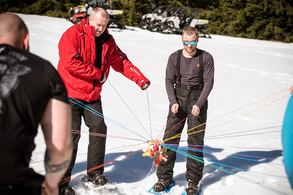 Teambuilding Aufgabe im Schnee bei einem Schneeschuh Event von team projekt, Teilnehmer lösen gemeinsam eine Gruppenübung als Teil eines Firmenincentives im Winter