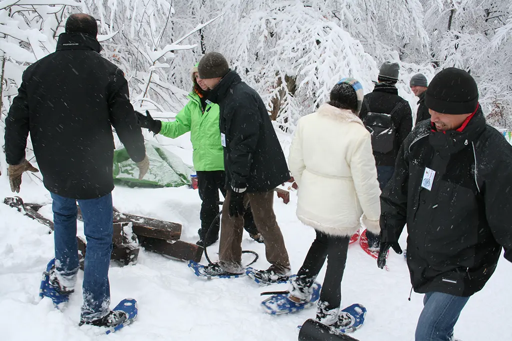 Teilnehmer bei einer Schneeschuhwanderung im verschneiten Wald, Winterevent von team projekt für Firmen mit Incentive und Teambuilding Programm
