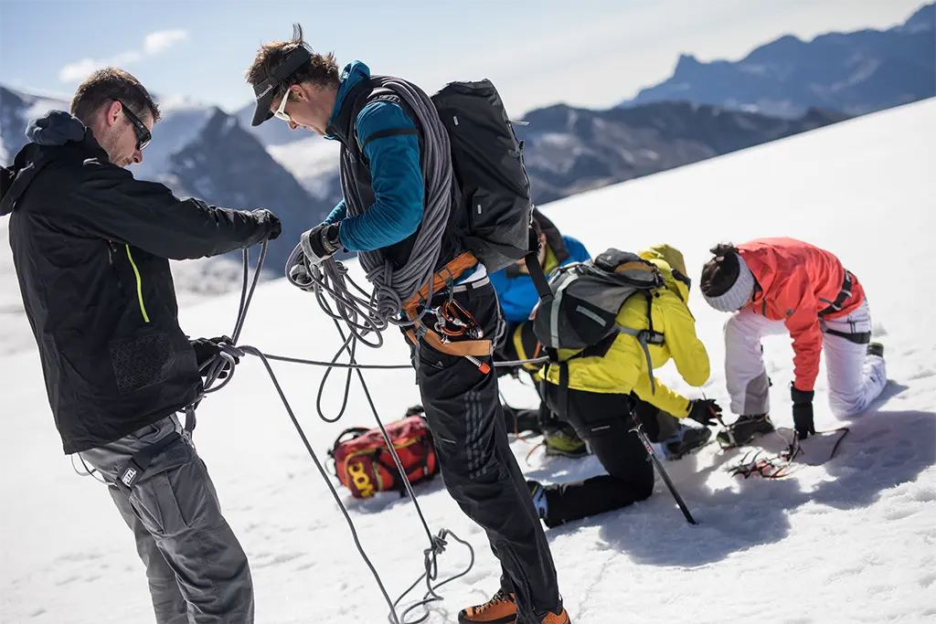 Teilnehmer sichern sich mit Kletterseilen bei einer alpinen Schneeschuh Tour, Outdoor Adventure und Corporate Teambuilding Event von team projekt in den Bergen