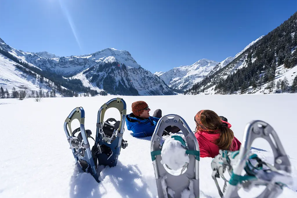 Teilnehmer entspannen sich während einer Schneeschuhtour in Oberstdorf im Allgäu. Eine Schneeschuhwanderung im Rahmen eines genussvollen Winterincentive und Teamevent vom Allgäu Eventspezialisten team projekt