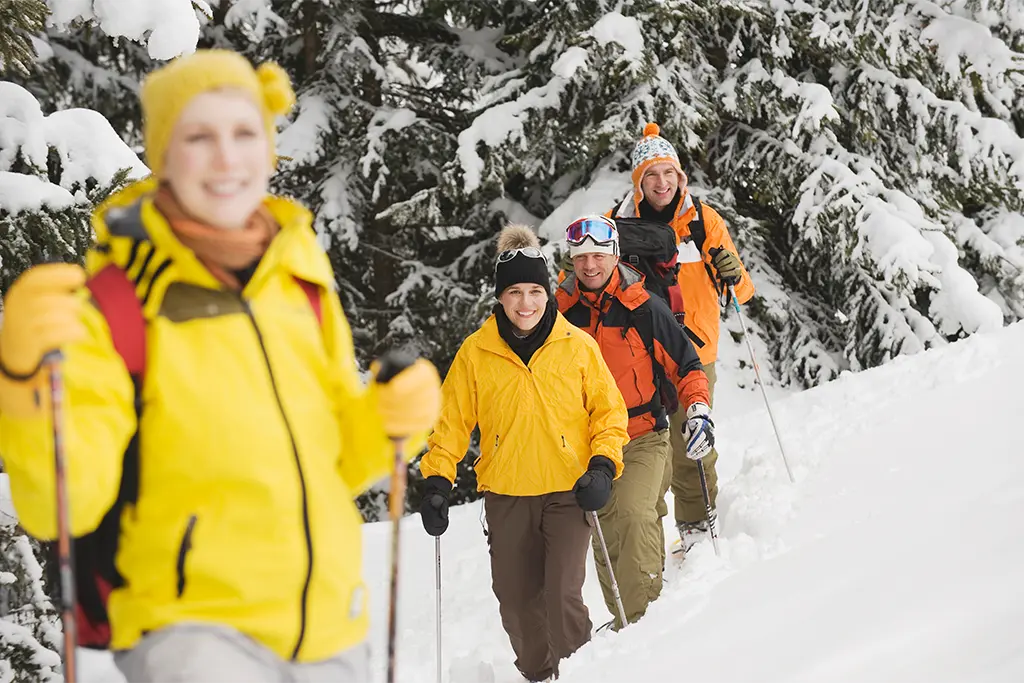 Schneeschuhwandertour mit 4 Teilnehmern bei einem Firmenevent im Schnee in Viechtach inmitten des Bayerischen Wald. Die Eventteilnehmer haben Spaß und lachen bei der Schneeschuhtour