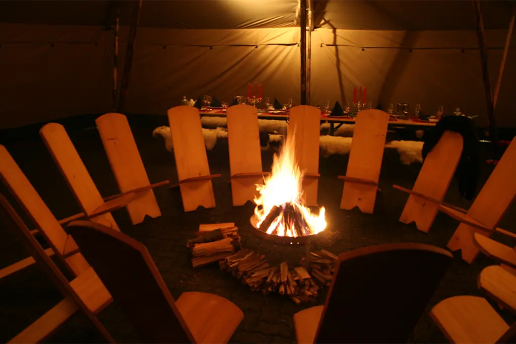 Gemütliches Lagerfeuer mit Sitzkreis in einer Winterlocation von team projekt, stimmungsvolles Rahmenprogramm für Firmen Incentives und Teamevents im Schnee