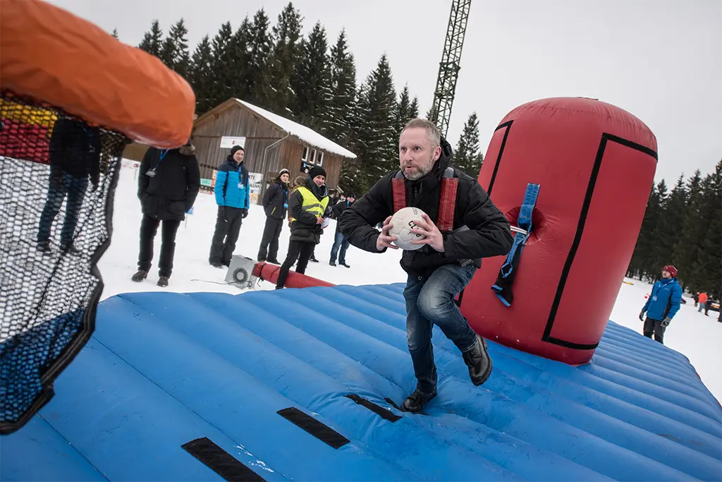 Ein Teilnehmer beim Bungeerun im Schnee als Teil einer  Winterteamolympiade in Bad Schandau in der Sächsischen Schweiz. Die anderen Teilnehmer des Teamevents feuern der Bungeerun Teilnehmer an