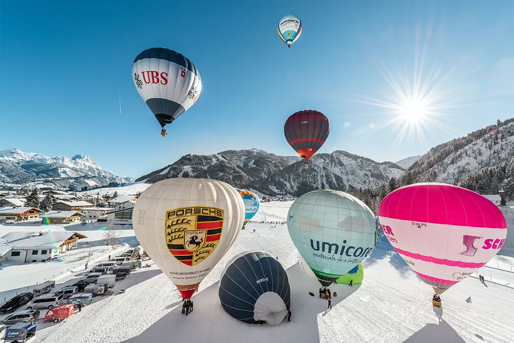 Heißluftballons im Winter die bei einem Schnee Incentive im Tannheimer Tal aufsteigen und über die Alpen fliegen. Organsiert von der Livemarketingagentur die Erlebniscompany