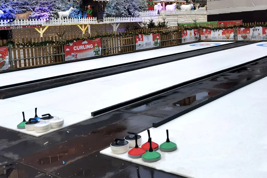 Eine große mobile Eisstockbahn als Teil einer Weihnachtsfeier in Karlsruhe. Auf dem Foto sieht man mehrere Eisstockbahnen, die man sich von dem  Eventveranstalter projekt für Winterevents anmieten kann