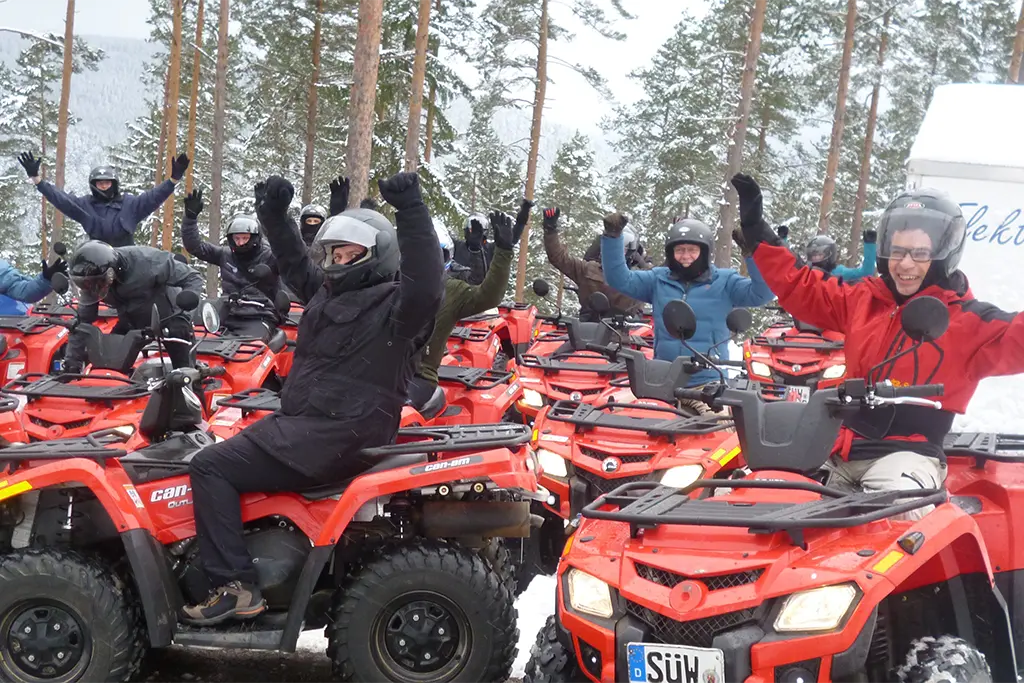 Eine Gruppe bei einem Firmenevent im Schnee die auf Quads sitzt und jubelt. Das Foto entstand bei einem Winter-Quadevent im Schwarzwald