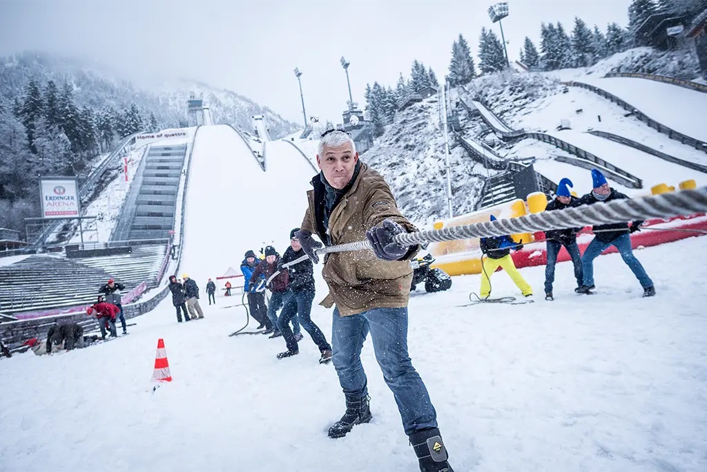 Mehrere Eventteilnehmer bei einem Winterevent in Oberstdorf an einem Tau. Bei dem Foto handelt es sich um ein Schnee-Teamevent in der Orlen Arena Oberstdorf Allgäu für ein Automotiveevent. 