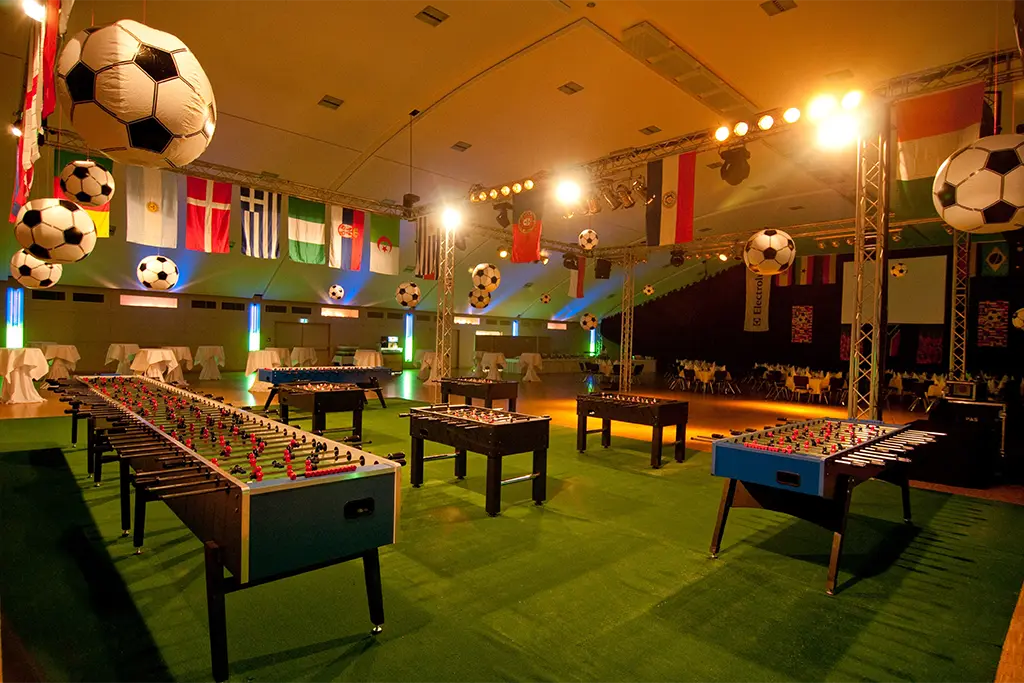 Große und kleine Tischkicker für ein XXL Tischkicker-Turnier mit Fußballdekoration aufgebaut. Das Bild zeigt eine Fußball-Themenparty in der Eventhalle des Sauerlandstern in Willingen im Sauerland.